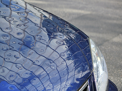 damages caused by hail on car before repair by paintless dent removal